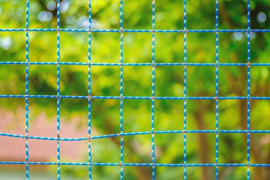 Steel wire mesh fence with green natural blur background