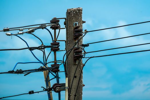 Electric pole with insulators and wires on blue sky