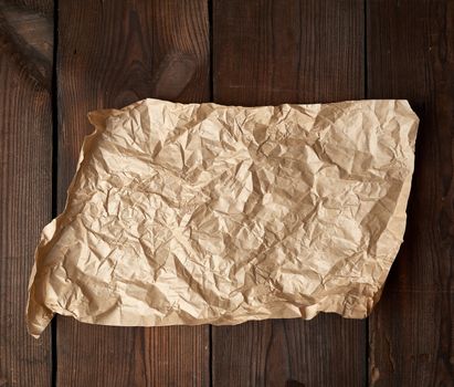 empty torn piece of brown crumpled baking paper on a table of boards, top view