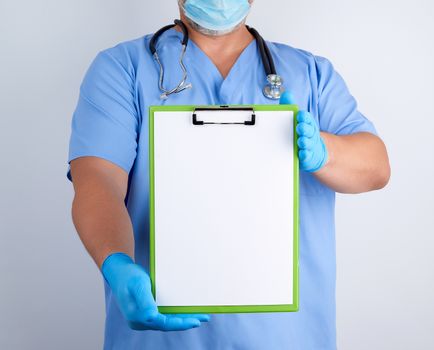 doctor in blue uniform and latex gloves holds a green holder for sheets of paper, empty space for writing text, white background