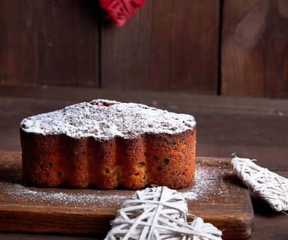 traditional European Stollen cake with nuts and candied fruit, brown wooden background 