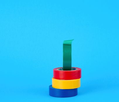 full coils of multi-colored insulating tape on a blue background, copy space