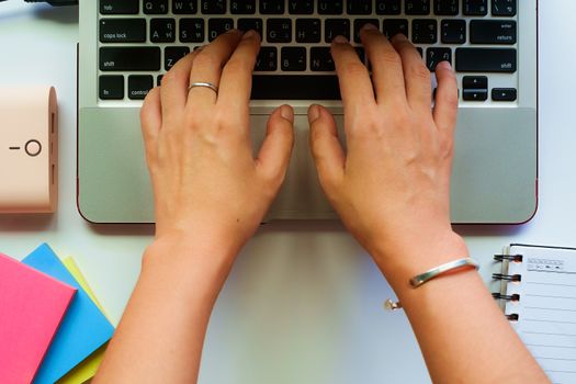 Top view of woman's hands working and typing on computer laptop with the white table workplace