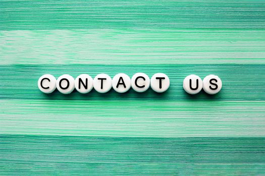 Contact us text on a green wooden table