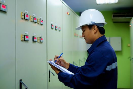 Engineer checking and monitoring the electrical system in the control room