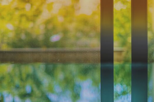 Opened door wire mesh screen with blurred natural background and vintage retro color tone