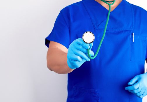 doctor in blue uniform and sterile gloves holding a medical stethoscope, copy space