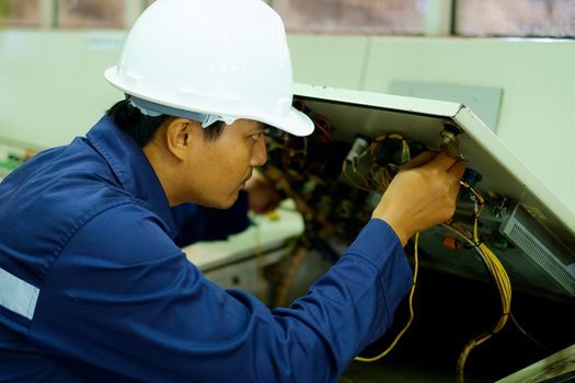 Engineer checking and repairing the electrical system in the control room