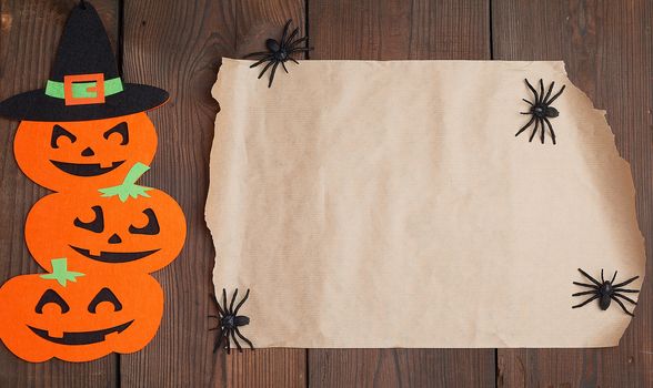 piece of brown paper and orange pumpkin felt figures on a brown background, Halloween festive backdrop