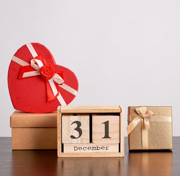 wooden retro calendar from blocks, Christmas decorative tree and cardboard boxes with gifts, white background