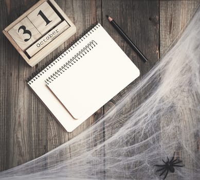 black spider figurines and wooden retro clock made of blocks with the date of October 31 on a gray wooden background, Halloween holiday