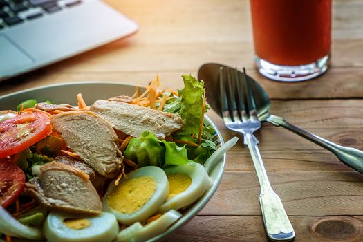 Vegetable salad with sliced egg and pork on wooden work table
