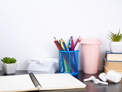 spiral notebooks, ceramic cup with coffee and colorful pencils on a black table, work space