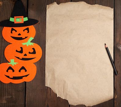 piece of brown paper and orange pumpkin felt figures on a brown background, Halloween festive backdrop