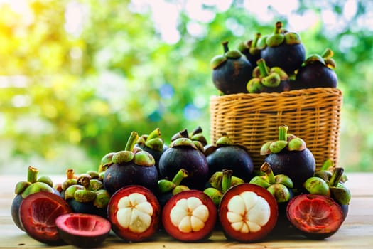 Mangosteen fruit in the basket on wooden table with blurred green background