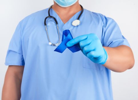 doctor in blue uniform and sterile latex gloves holds a dark blue ribbon, concept of timely research and disease prevention colon malignancies, chronic fatigue syndrome, tuberous sclerosis