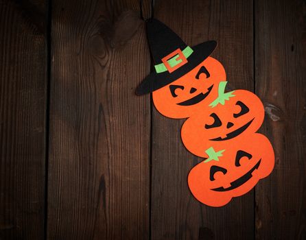 orange pumpkin felt figures on a brown background, Halloween festive backdrop