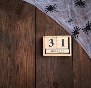 black spider figurines and wooden retro clock made of blocks with the date of October 31 on a brown wooden background, Halloween holiday