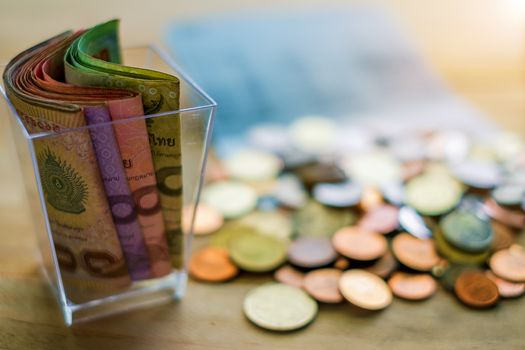 Thai baht money banknotes and coins on the wood table, business and finance concept