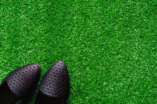 Black shoes on the plastic artificial green grass