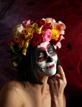 Portrait of a young girl with makeup in the image of Katrina for the holiday of the Day of the Dead. Sugar skull makeup. spider web background with black spiders