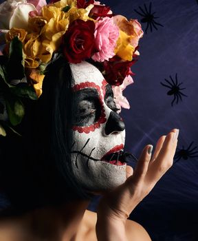 Young beautiful girl with traditional mexican death mask. Calavera Catrina. Sugar skull makeup. girl dressed in a wreath of roses on a background of white web