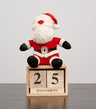 santa claus in red hat, table wooden calendar with the date december 25, christmas background