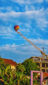 Colorful hot air balloon floating in the position of the construction cane on the blue sky background