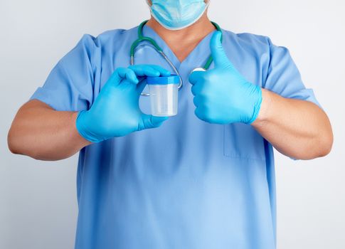 doctor in blue uniform and latex gloves is holding an empty plastic container for taking urine samples, left hand shows gesture like