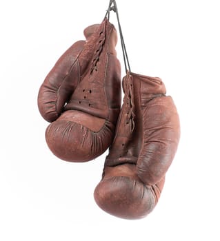 pair of very old vintage brown leather boxing gloves hanging on a black rope, object isolated