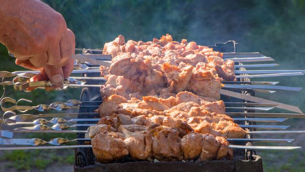 The chef prepares meat in a cafe or restaurant. Fresh raw and fried pork, beef and lamb meat on a skewer. We fry shish kebabs, barbecue, BBQ in the backyard in the summer on a weekend.