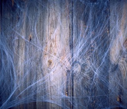 white spider web in the corner of the composition, gray wooden background from old boards, backdrop  for Halloween holiday, copy space