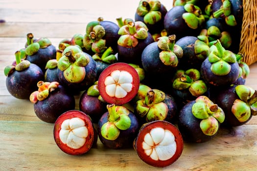 Mangosteen fruit in the basket on wooden table with blurred green background