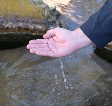 male palm scoops up water from a natural source, concept of lack of natural resources
