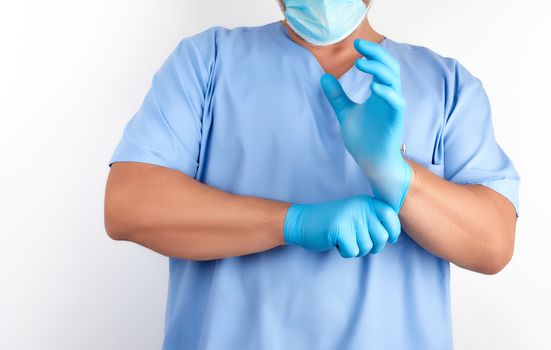 male doctor in blue uniform puts on his hands white sterile latex gloves before surgery, white background