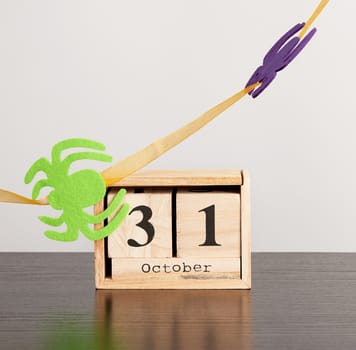 wooden calendar of cubes with the date October 31 on a black table, celebration of Halloween, minimalism