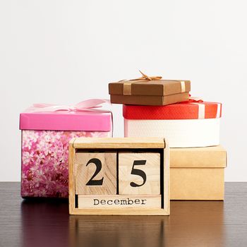 wooden calendar of cubes with the date of December 25 and a stack of boxes with gifts, festive Christmas background