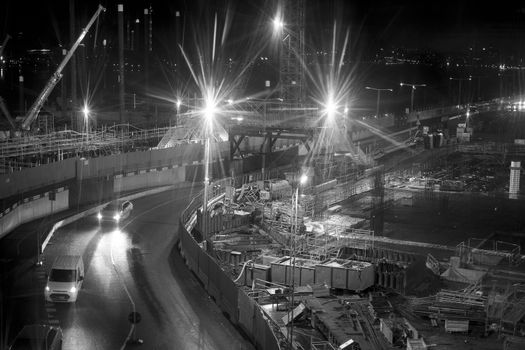Black and white image of construction site with bright lights.