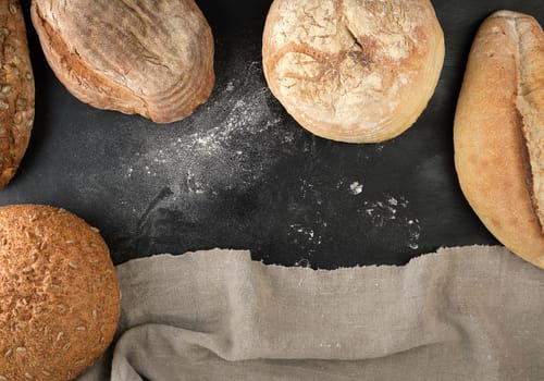baked various loaves of bread on a black background, empty space, top view