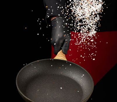 chef holds a round pan and throws the mixture of spices and white salt up, low key