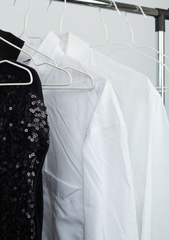 black women's blouse with red sequins, white men's shirts hang on a white iron hanger, sale concept