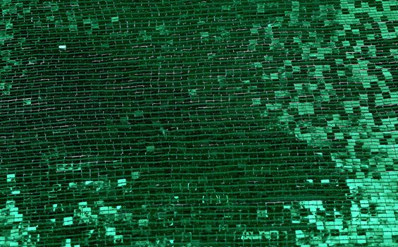 fragment of fabric embroidered with green square sequins, full frame