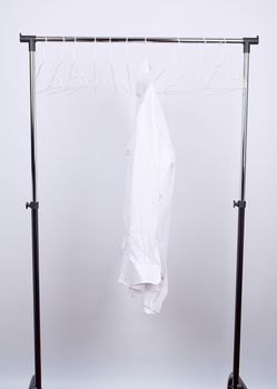 white men's crumpled shirt hanging on a metal hanger, white background, concept of loneliness