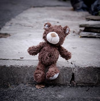 little teddy bear sitting on the side of the road during the day, loneliness concept