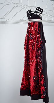 black women's blouse with red sequins hanging on a white iron hanger, sale concept