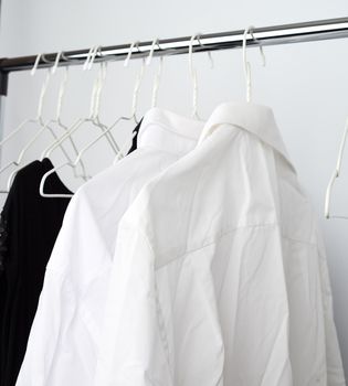 white men's crumpled shirts hanging on a metal hanger, white background