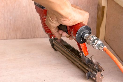 Hands of artisan furniture with an air gun to shoot for the wood.