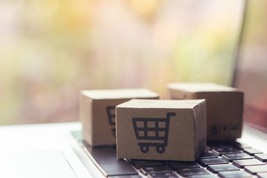 Online shopping - Paper cartons or parcel with a shopping cart logo on a laptop keyboard. Shopping service on The online web and offers home delivery.