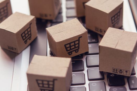 Online shopping - Paper cartons or parcel with a shopping cart logo on a laptop keyboard. Shopping service on The online web and offers home delivery.