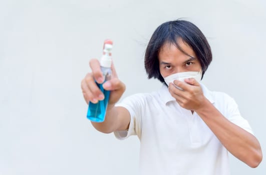 A asian man wear mask and spray the alcohol gel for cleaning disease